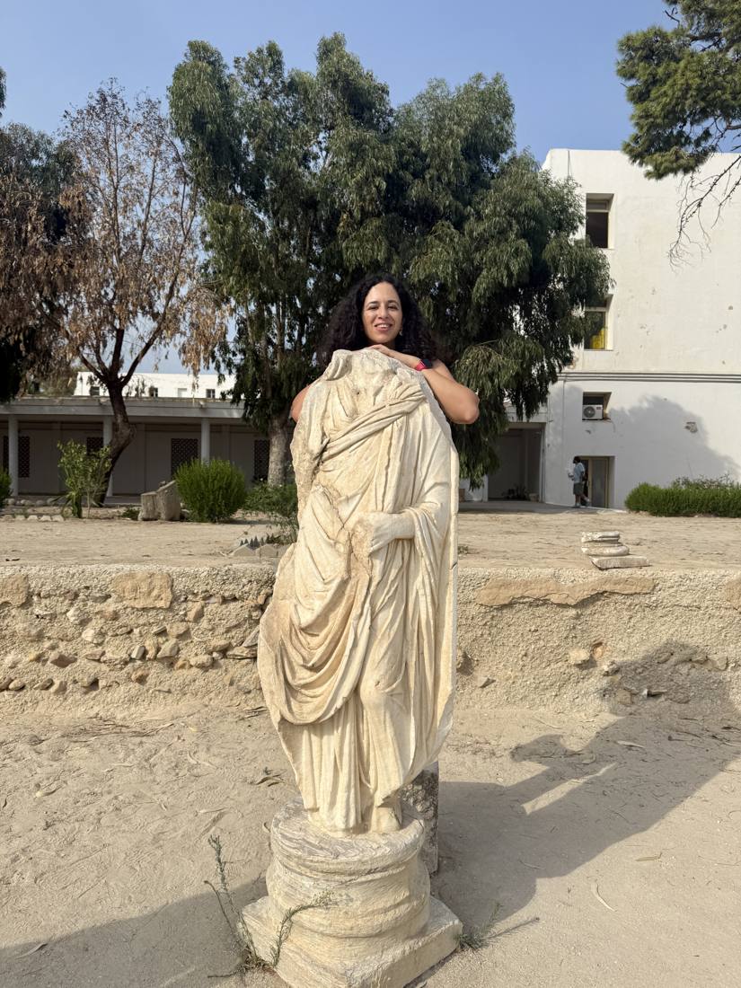 Ines Said imitant la pose d'une statue antique sur un site de fouilles en Tunisie